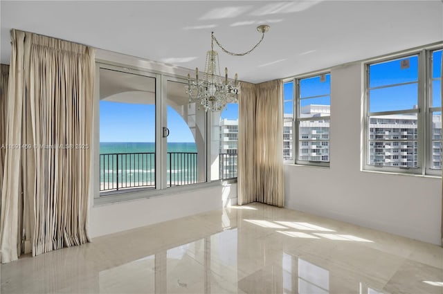 unfurnished room featuring an inviting chandelier and a water view