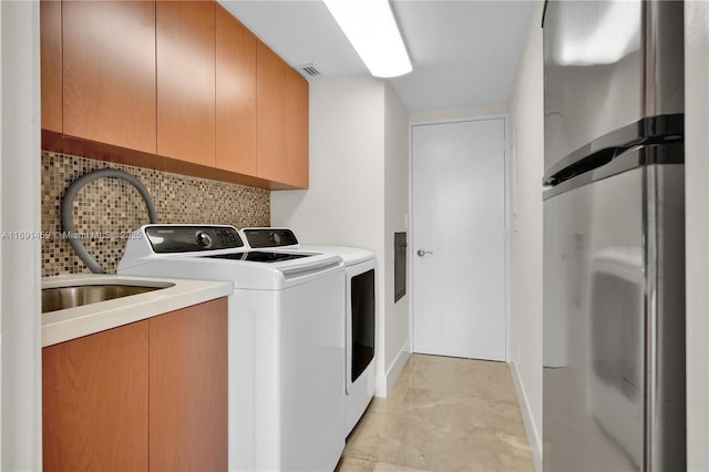 clothes washing area featuring washing machine and dryer, sink, and cabinets