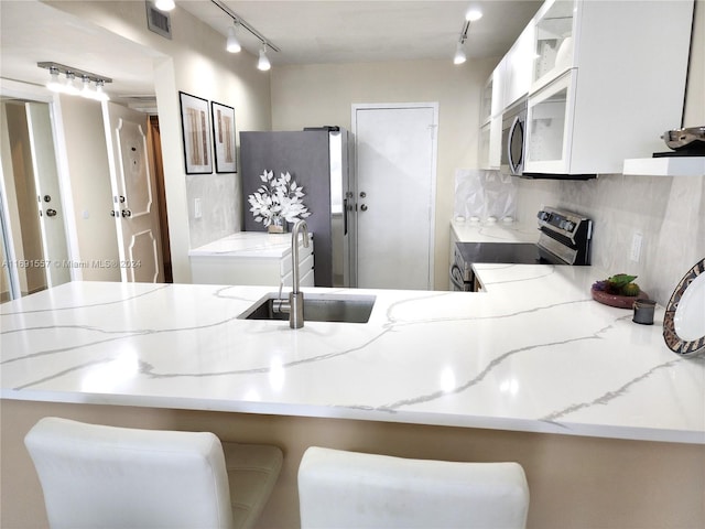 kitchen with kitchen peninsula, appliances with stainless steel finishes, a breakfast bar, and white cabinets