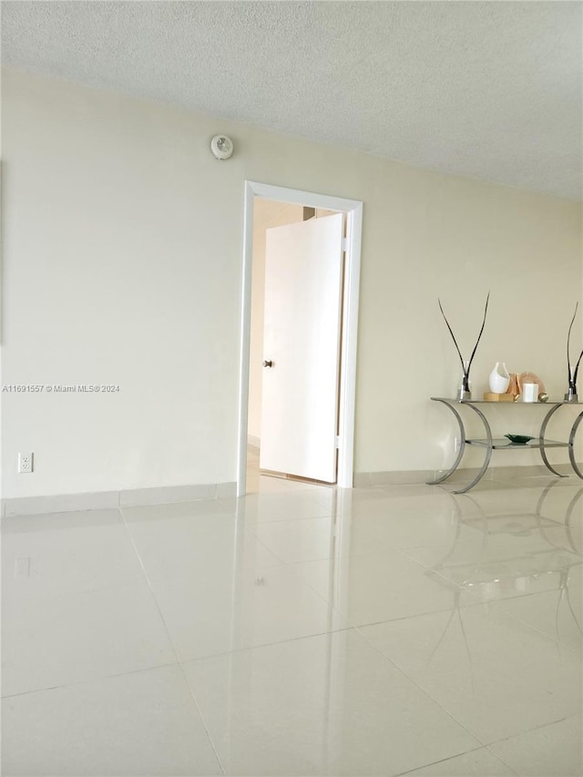 unfurnished room featuring a textured ceiling and tile patterned floors