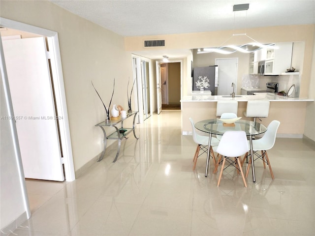 tiled dining space with a textured ceiling and sink