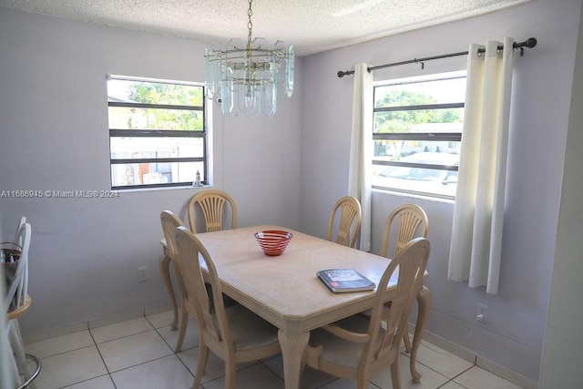 tiled dining area with plenty of natural light, an inviting chandelier, and a textured ceiling