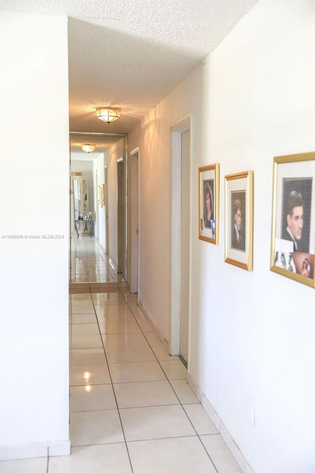 hallway featuring a textured ceiling and light tile patterned floors