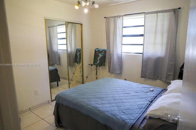 tiled bedroom with a closet and a chandelier