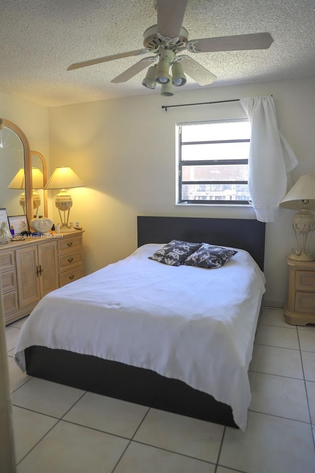 bedroom with a textured ceiling, ceiling fan, and light tile patterned flooring