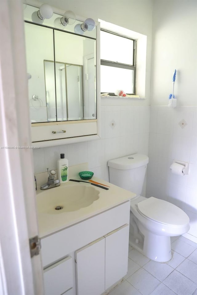 bathroom featuring toilet, vanity, tile walls, and tile patterned flooring