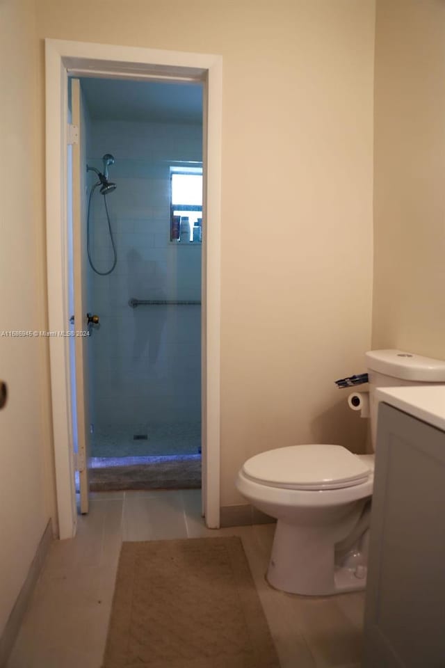 bathroom featuring toilet, vanity, tile patterned flooring, and a tile shower