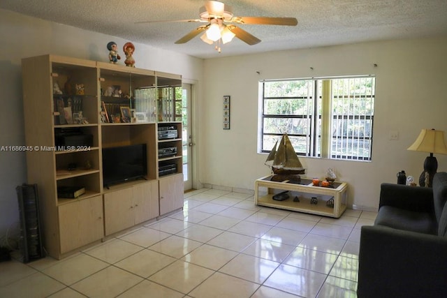 living room featuring a textured ceiling, ceiling fan, and light tile patterned floors