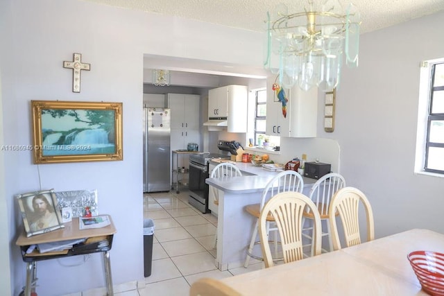 tiled dining space with a textured ceiling, a healthy amount of sunlight, and an inviting chandelier