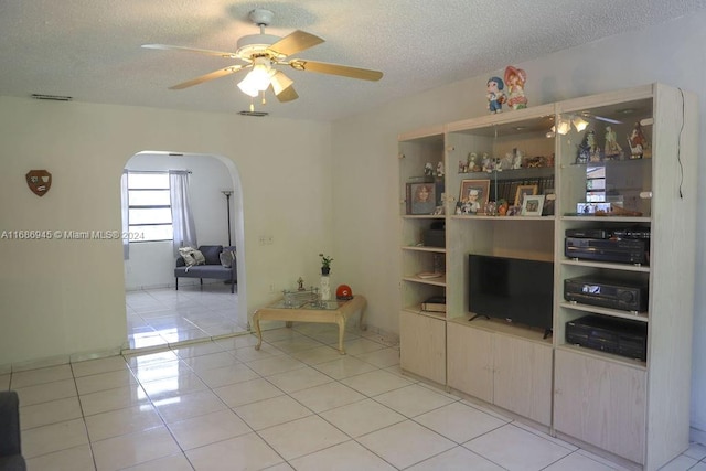 unfurnished living room featuring light tile patterned flooring, ceiling fan, and a textured ceiling