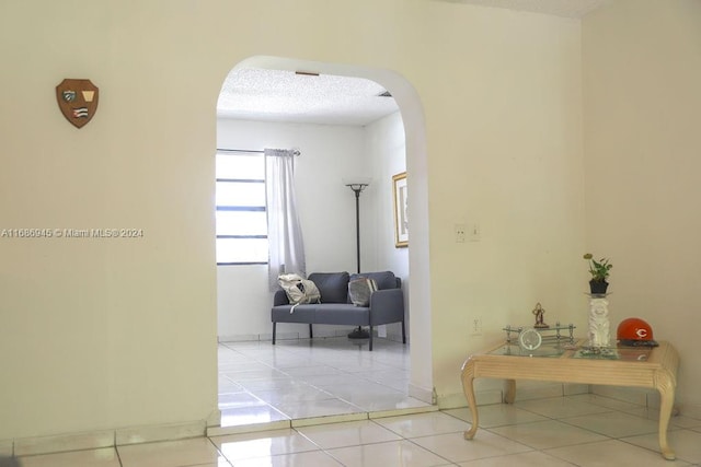 corridor featuring a textured ceiling and light tile patterned flooring