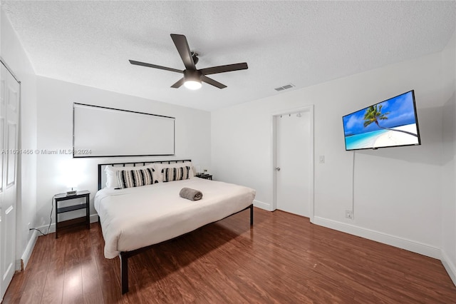 bedroom featuring a textured ceiling, dark hardwood / wood-style floors, and ceiling fan