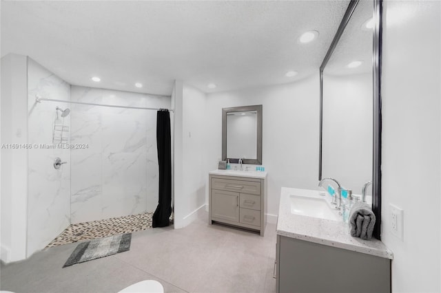 bathroom featuring vanity, a tile shower, and a textured ceiling