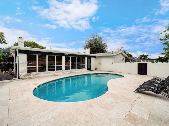 view of pool with a sunroom and a patio area