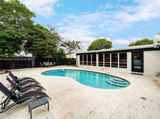 view of swimming pool with a patio area and a sunroom