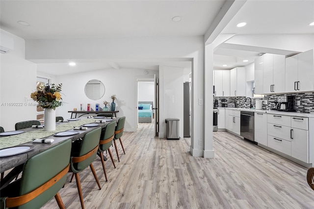 kitchen featuring stainless steel dishwasher, backsplash, light hardwood / wood-style floors, and white cabinets