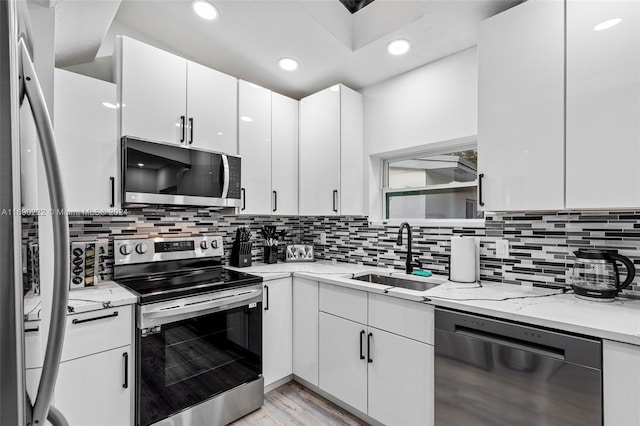 kitchen featuring backsplash, white cabinets, sink, and stainless steel appliances