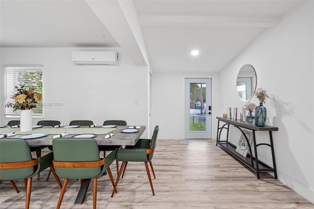 dining room with a wall unit AC, beamed ceiling, and light hardwood / wood-style floors