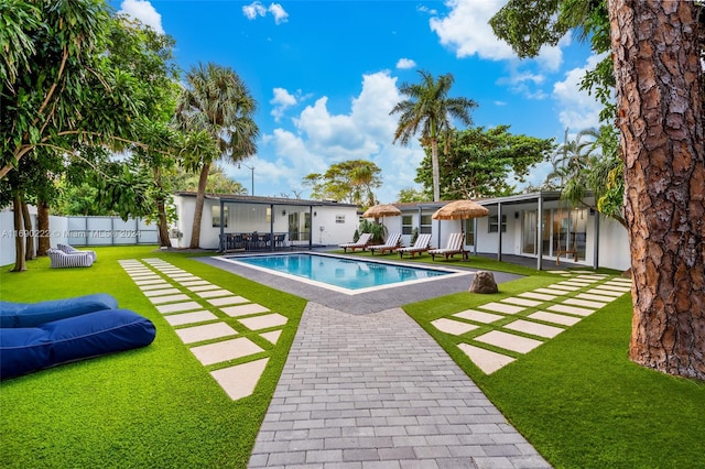 view of pool with a lawn, a sunroom, and a patio