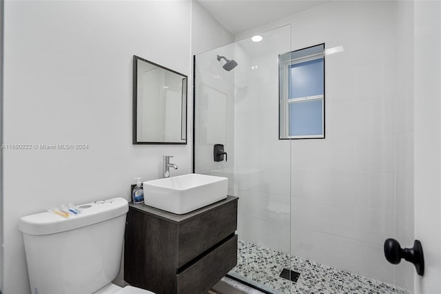 bathroom featuring toilet, vanity, and a tile shower