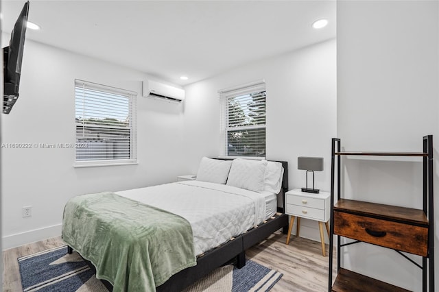 bedroom with multiple windows, wood-type flooring, and a wall mounted air conditioner