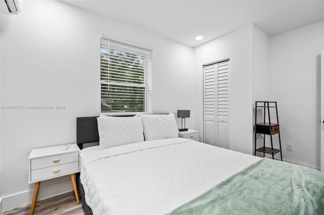 bedroom featuring a wall mounted AC, wood-type flooring, and a closet