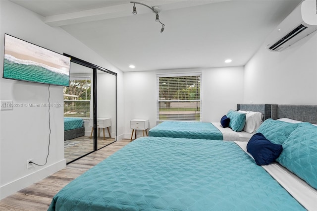 bedroom featuring a closet, light wood-type flooring, lofted ceiling, and a wall mounted air conditioner