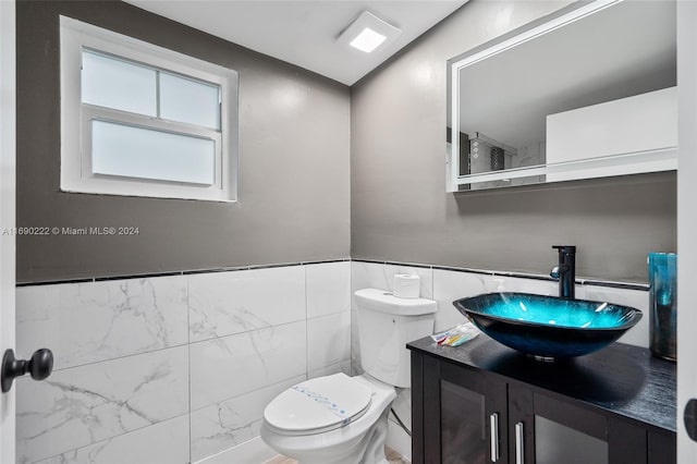 bathroom with tile walls, vanity, and toilet