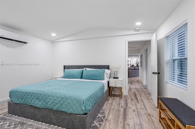 bedroom with hardwood / wood-style flooring, an AC wall unit, and vaulted ceiling