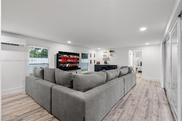 living room featuring a wall mounted air conditioner and light hardwood / wood-style floors