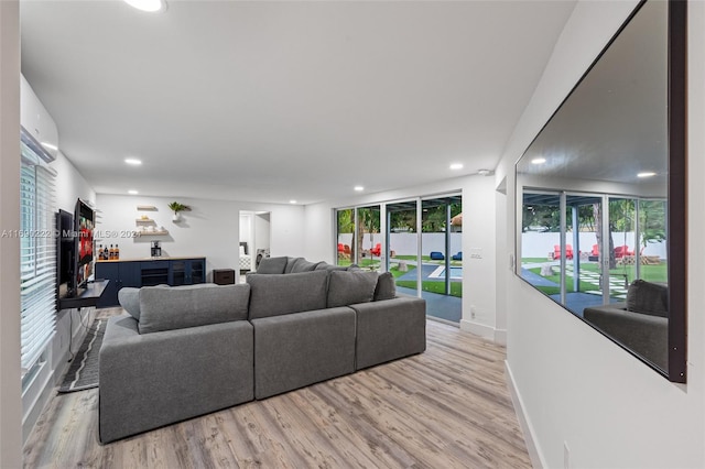 living room featuring light hardwood / wood-style floors, a healthy amount of sunlight, and an AC wall unit