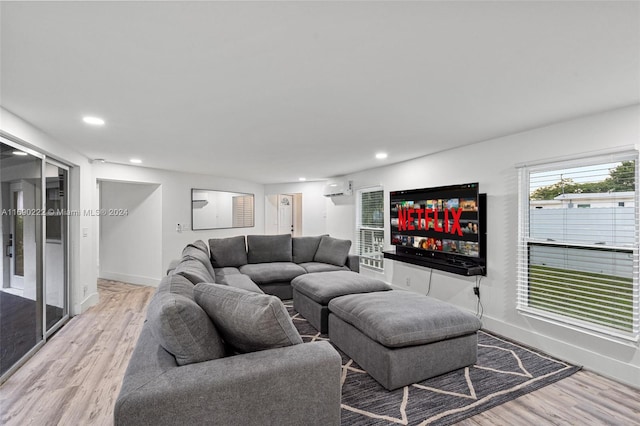 living room with a wall mounted AC and light wood-type flooring