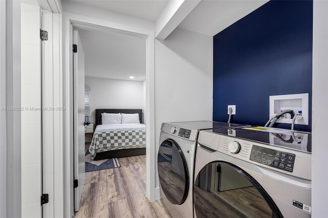 clothes washing area featuring light wood-type flooring and washer and dryer