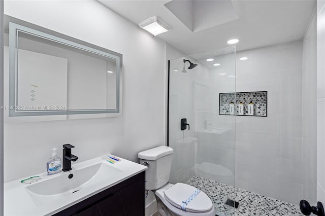 bathroom with tiled shower, vanity, and toilet