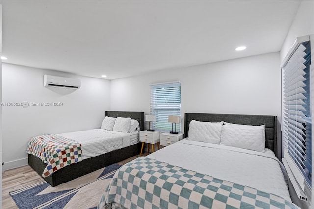 bedroom featuring light hardwood / wood-style floors and a wall mounted AC