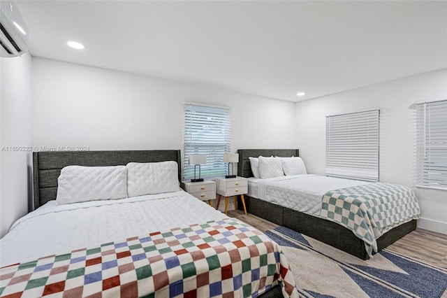 bedroom with a wall unit AC and wood-type flooring