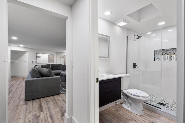 bathroom with hardwood / wood-style floors, a shower with door, vanity, and toilet