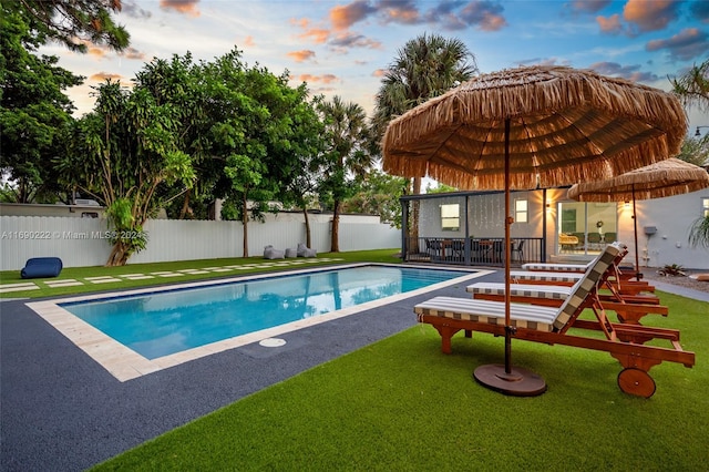 pool at dusk featuring a yard