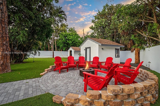 patio terrace at dusk with an outbuilding, a yard, and a fire pit