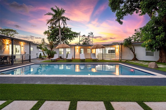 pool at dusk featuring a patio and a yard