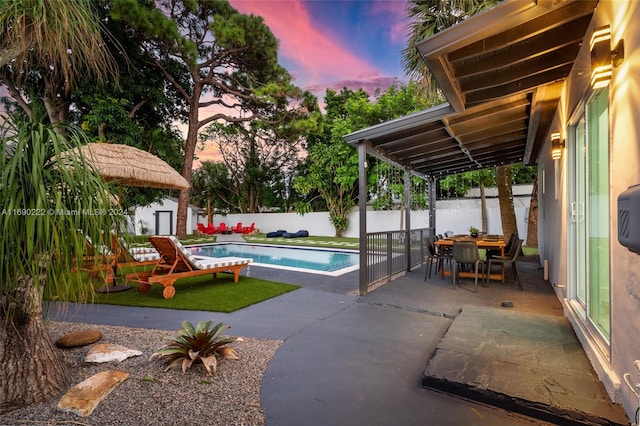 pool at dusk with a shed and a patio area