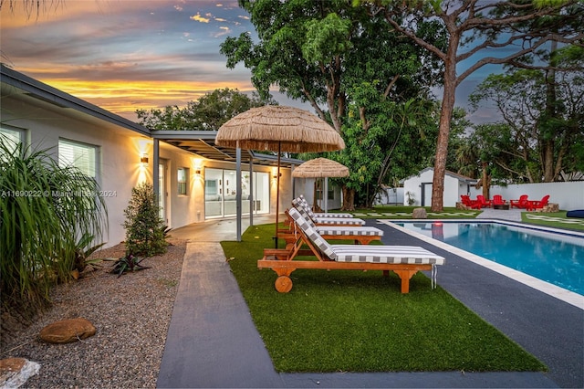 1899 NE 49th Ct, Pompano Beach, FL 33064 - pool at dusk with a patio and a yard