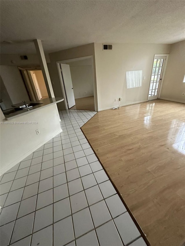 unfurnished living room featuring a textured ceiling and light tile patterned flooring