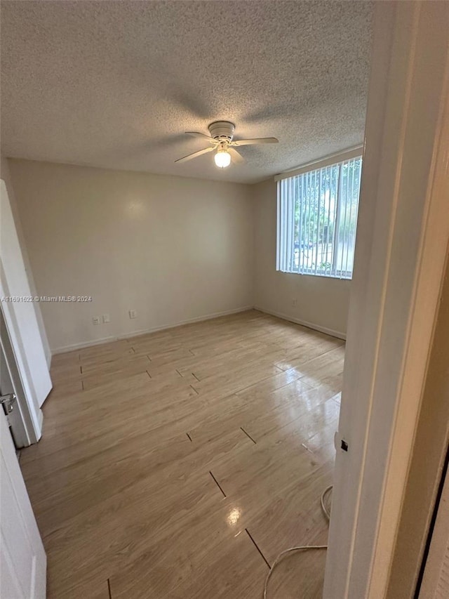 empty room featuring light hardwood / wood-style floors, a textured ceiling, and ceiling fan