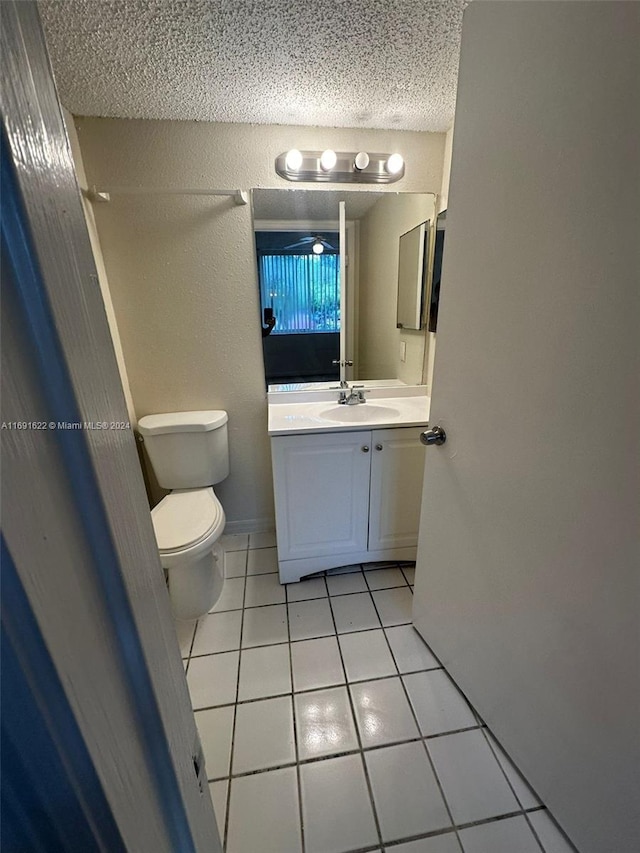 bathroom featuring toilet, vanity, a textured ceiling, and tile patterned flooring