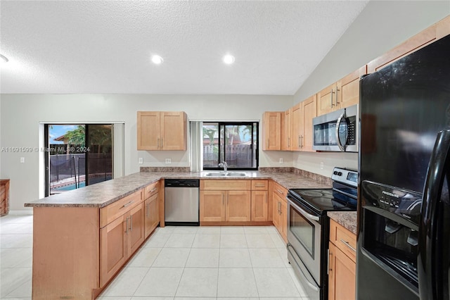 kitchen featuring sink, kitchen peninsula, lofted ceiling, light tile patterned floors, and appliances with stainless steel finishes