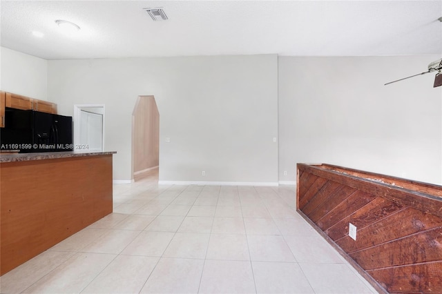 kitchen with ceiling fan, light tile patterned flooring, black fridge, and a textured ceiling