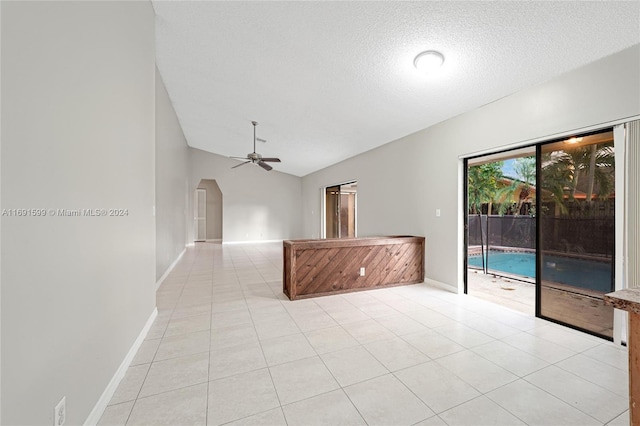 empty room with light tile patterned floors, a textured ceiling, ceiling fan, and lofted ceiling