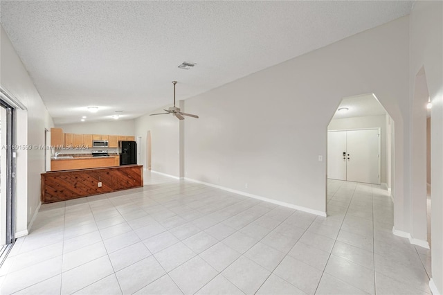 unfurnished living room with ceiling fan, light tile patterned floors, and a textured ceiling