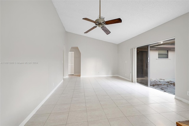 tiled spare room featuring a textured ceiling, vaulted ceiling, and ceiling fan